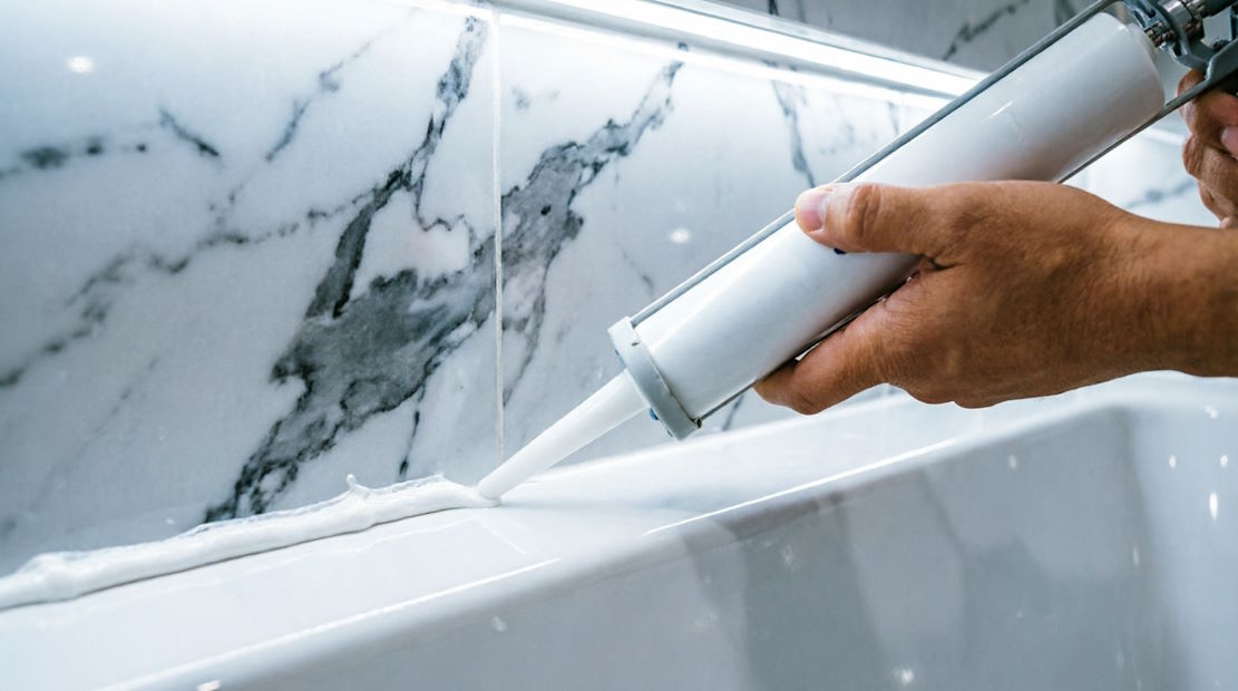 Нанесение силиконового герметика на шов между ванной и стеной